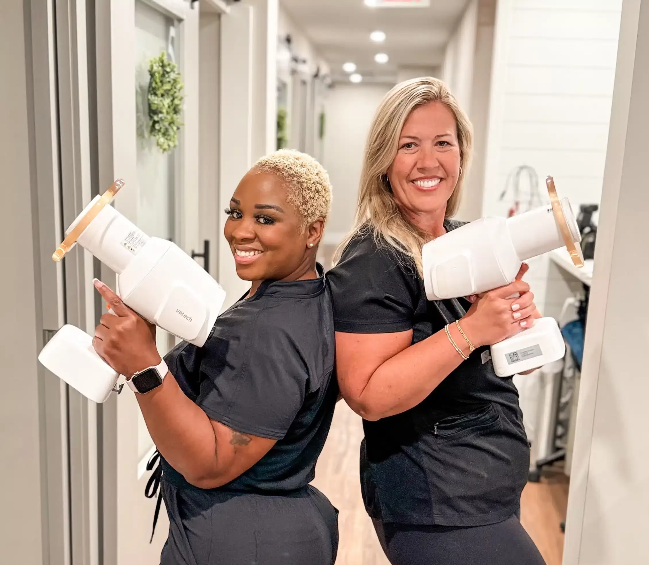 Two Alpharetta Smile Care team members posing in the hallway with oversized tooth props