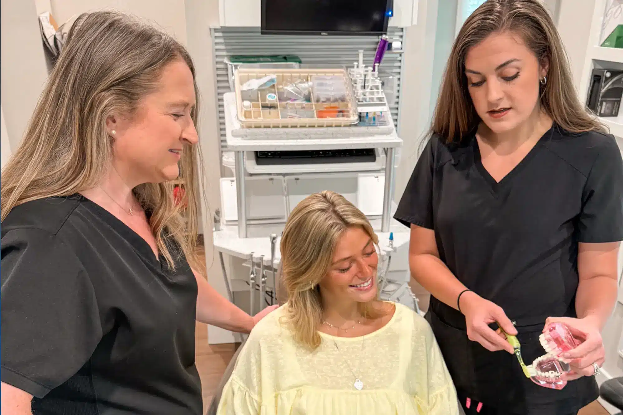 Team members showing a patient a dental bridge model