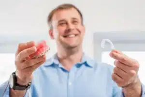 Man comparing a braces model with a clear aligner