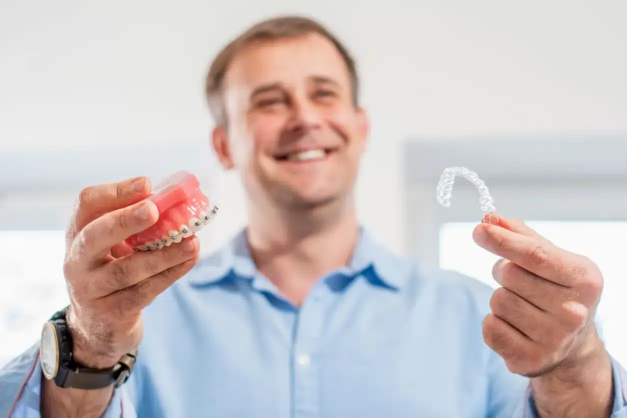 Man comparing a braces model with a clear aligner