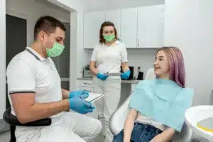 Dentist and assistant talking with a patient in the dental chair